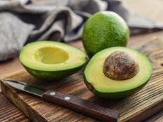 Fresh avocado on cutting board over wooden background