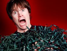 Man overwhelmed by the tangled Christmas lights he's pulled out of storage.
