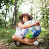 I love my planet: Young scout girl embracing world globe.