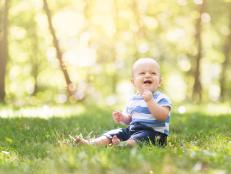 Fraternal twin boy cheerfully plasy with outside in the grass in the summer months of Iowa.