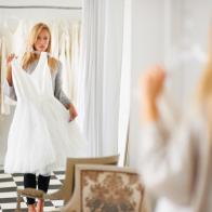 A young bride looking at her reflection in a mirror while choosing a dress