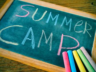 text summer camp written with chalk on a chalkboard, and some chalk sticks of different colors