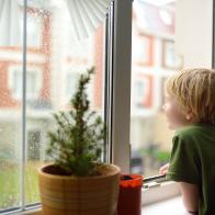 Little boy watching the rain outside at opened window. Bad weather - wind and downpour. Child boring and waiting of rainfall finish. Inquisitive kid explore nature.
