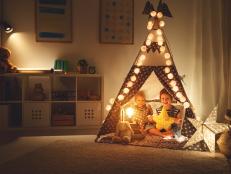 happy family loving children brother and sister play, laugh and hug   in dark tent in playroom at home