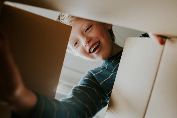 Happy young box opening a cardboard box and reaching in. Conceptual with space for copy.