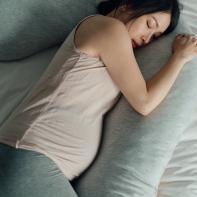 Elevated view of Asian Pregnant woman resting in bed. Comfortable sleeping positions during pregnancy. Tiredness and sleep problems during pregnancy.