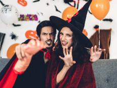 Couple having fun wearing dressed carnival halloween costumes and makeup posing with bats and balloons on background at the halloween party.Halloween holiday celebration concept