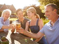 Parents With Adult Offspring Enjoying Outdoor Summer Drink At Pub