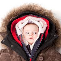 Concept portrait of a cute 3 month baby girl in many winter jackets.