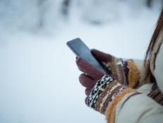 Female hands holding a cellphone outdoors in the snow