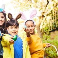 Children having fun on an Easter Egg hunt showing their eggs and carrying easter baskets.