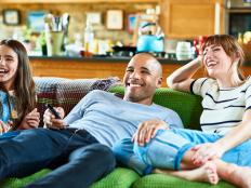 Happy family reclining on green sofa and watching TV