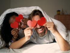 Young happy couple in bed with hearts in the eyes