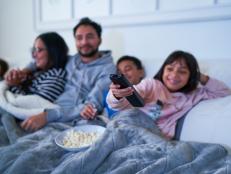 Family relaxing on living room sofa and watching TV with popcorn at night
