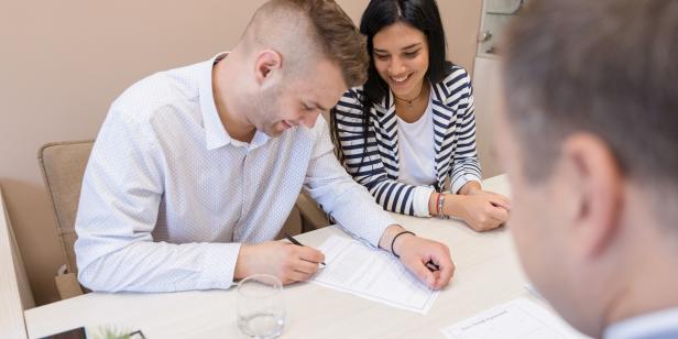 Young married couple signs the contract in the presence of their lawyer.
Prenuptial Agreement