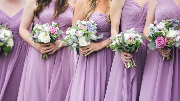 Bridesmaids in pink and vioilet dresses holding floral arrangements. CLose up of bridal party with bouquets.