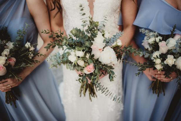 Bride and bridesmaids in blue dresses with bunches of white roses