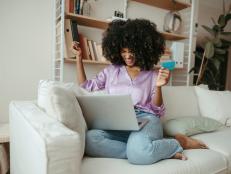 Happy woman with credit card doing online shopping on laptop at home