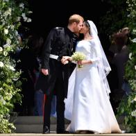 WINDSOR, UNITED KINGDOM - MAY 19: Britain's Prince Harry, Duke of Sussex kisses his wife Meghan, Duchess of Sussex as they leave from the West Door of St George's Chapel, Windsor Castle, in Windsor on May 19, 2018 in Windsor, England. (Photo by  Ben STANSALL - WPA Pool/Getty Images)