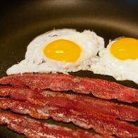 Fried eggs and bacon cooking in a skillet