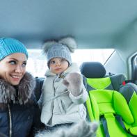 Mother and baby daughter bask in the car after a walk in a winter park. Happy family. Childhood and parenthood happiness. (Mother and baby daughter bask in the car after a walk in a winter park. Happy family. Childhood and parenthood happiness., ASCII