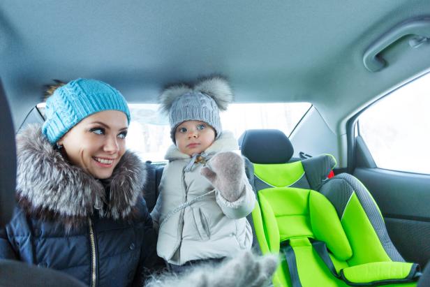 Mother and baby daughter bask in the car after a walk in a winter park. Happy family. Childhood and parenthood happiness. (Mother and baby daughter bask in the car after a walk in a winter park. Happy family. Childhood and parenthood happiness., ASCII