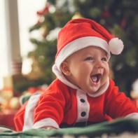 Cute baby laying down on the floor near Christmas tree.