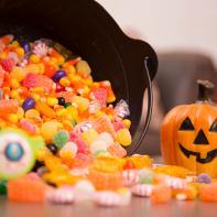 Halloween decor including jack o'lantern, candy bucket, spooky glasses.  Preparing for Halloween party or trick or treat children to arrive.  No people.