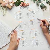 Wedding background with checklist and calendar. Female hands arranging marriage, filling in planners on white wooden table with lots of tender bridal stuff, top view