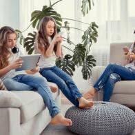 Education, friendship, technology and children concept. Group of teenage girls is using gadgets. Kids with phones and tablets, with smartphones and headphones.