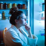 A young dieting woman standing in front of the refrigerator, contemplating and thinking about what to eat for hunger. Making choices and decision for healthy lifestyle