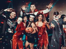 Portrait of Young Smiling People in Scary Costumes. Group of Young Happy Friends Wearing Halloween Costumes having Fun Together and posing for Group photo in Nightclub. Halloween Celebration