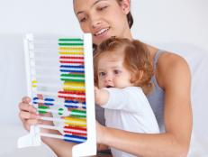 A young mother teaching her baby daughter the basics of mathematics by using an abacus