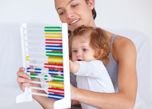 A young mother teaching her baby daughter the basics of mathematics by using an abacus