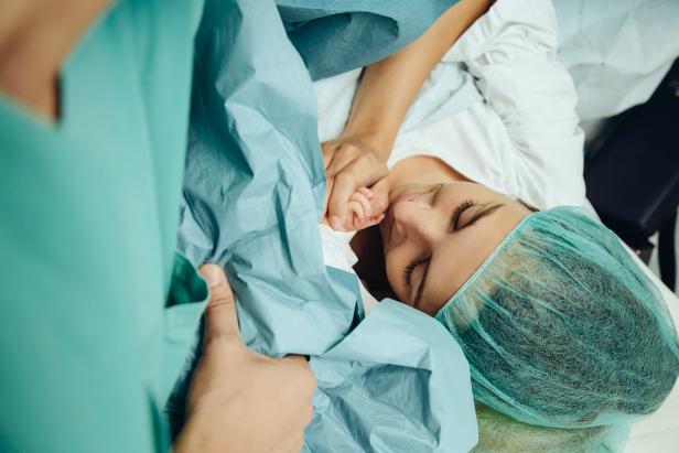 Mother touching hand of her newborn right after c-section