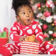 Surprised Black girl holding teddy bear toy on Christmas