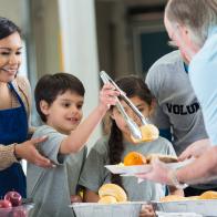 Young Hispanic family volunteering to serve food in soup kitchen