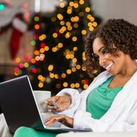 African American woman buying Christmas gifts online with credit card