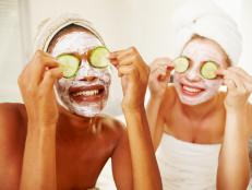 Multi-racial young women holding cucumbers over their eyes wearing face masks
