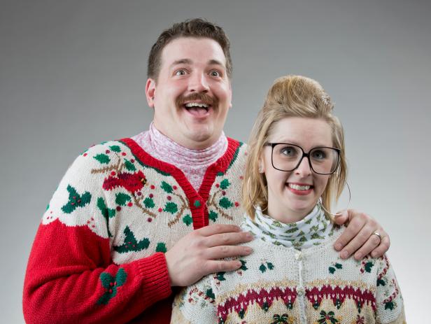 A couple of people dressed in their best ugly sweater, posing for a christmas photo.
