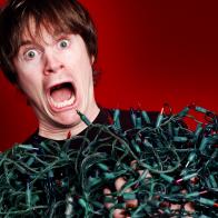 Man overwhelmed by the tangled Christmas lights he's pulled out of storage.