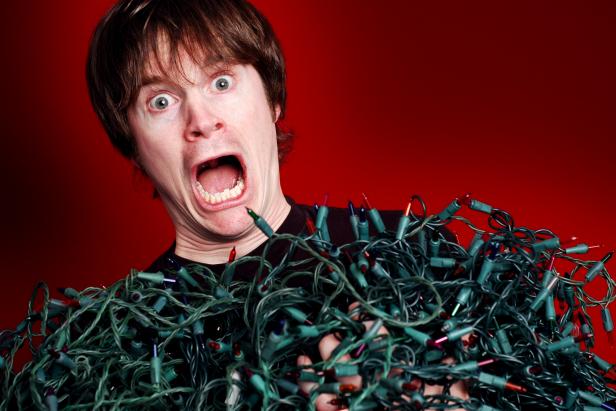 Man overwhelmed by the tangled Christmas lights he's pulled out of storage.