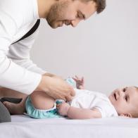 Young attractive father is changing nappy to his baby girl