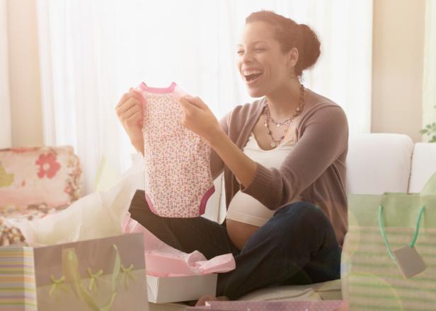 Pregnant mixed race woman opening gifts at baby shower