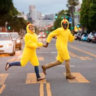 Couple in chicken costumes crossing city street