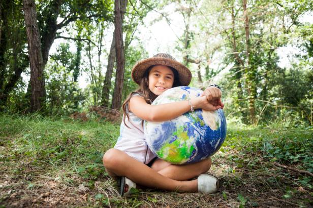 I love my planet: Young scout girl embracing world globe.