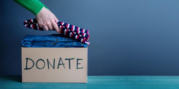 Donation Concept. Woman Preparing her Used Old Clothes into a Donate Box