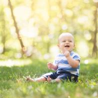 Fraternal twin boy cheerfully plasy with outside in the grass in the summer months of Iowa.