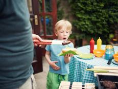 Little boy getting a hotdog at a family barbecue