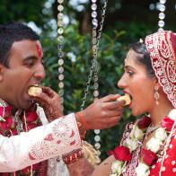 Bride and groom show respect by feeding each other indian sweets (burfi) during the Gujarati Hindu Indian ceremony